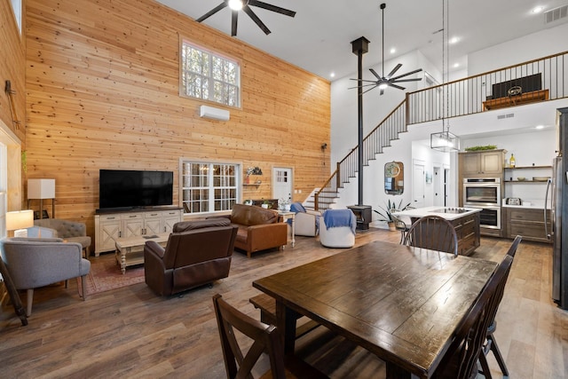 dining area featuring ceiling fan, wooden walls, and wood finished floors