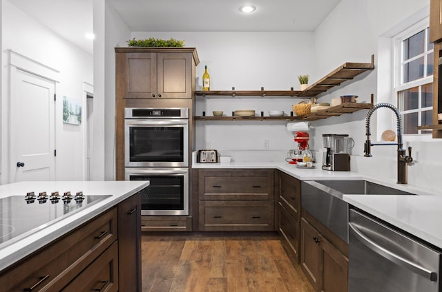 kitchen featuring a sink, light countertops, appliances with stainless steel finishes, dark wood-style floors, and open shelves