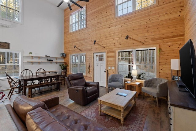 living area with a healthy amount of sunlight, wooden walls, and wood finished floors