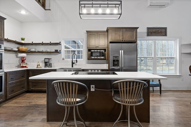 kitchen featuring a wall mounted air conditioner, a sink, light countertops, stainless steel appliances, and a wealth of natural light