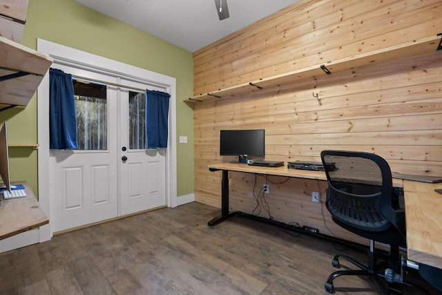 office area with wooden walls, dark wood finished floors, and a ceiling fan