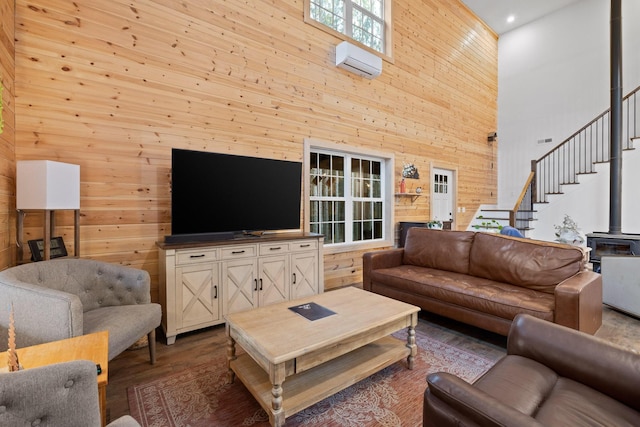 living room with stairway, a wall unit AC, wooden walls, and wood finished floors