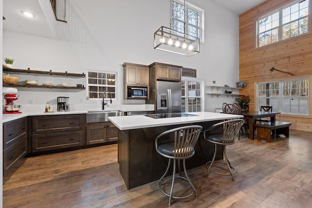 kitchen with open shelves, a sink, wood finished floors, built in microwave, and stainless steel fridge with ice dispenser