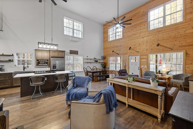 living room featuring ceiling fan, wooden walls, and wood finished floors