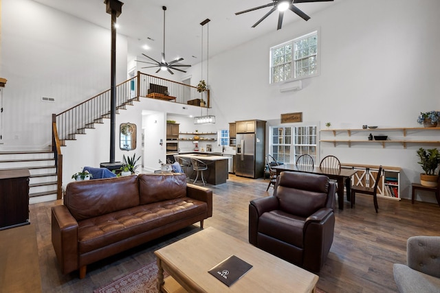 living room with visible vents, ceiling fan, wood finished floors, stairs, and an AC wall unit