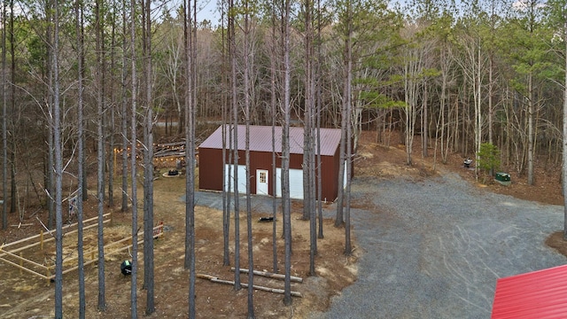 exterior space with an outbuilding, gravel driveway, and a view of trees