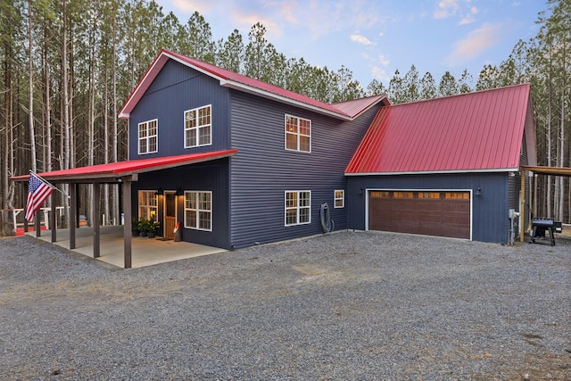 view of front of property featuring a garage, metal roof, and gravel driveway