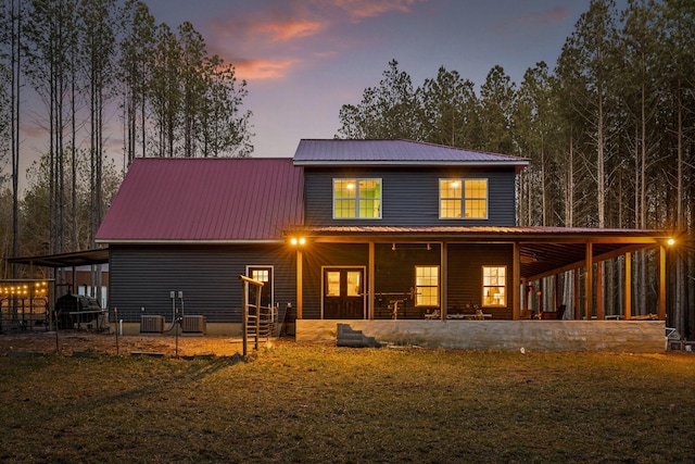 back of house at dusk with metal roof and cooling unit