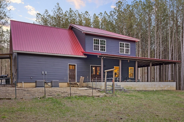 back of property with entry steps, metal roof, cooling unit, and a yard