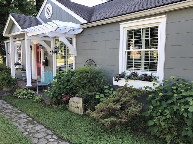 view of property exterior featuring a shingled roof and a pergola