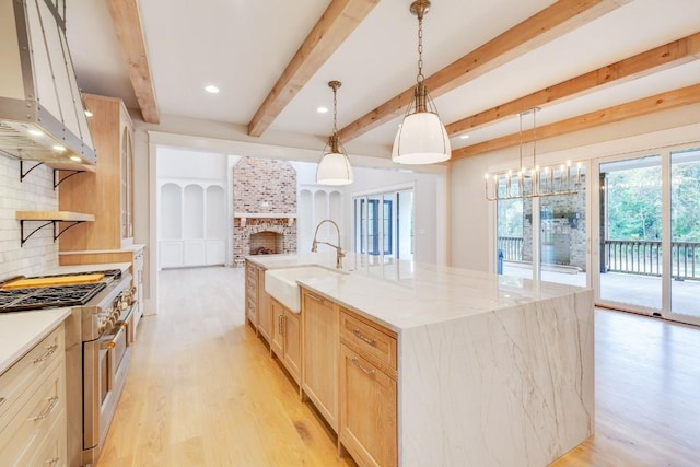 kitchen with high end stove, light brown cabinets, decorative backsplash, a fireplace, and a sink