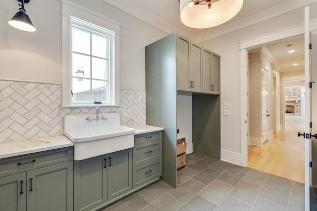 bathroom featuring tile patterned flooring, backsplash, crown molding, and a sink