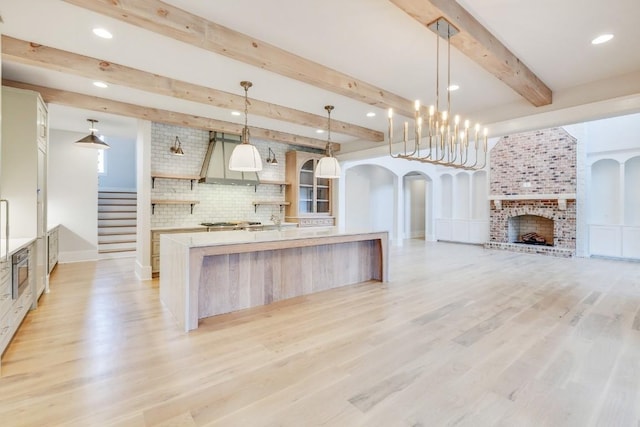 kitchen featuring a spacious island, tasteful backsplash, arched walkways, a fireplace, and light countertops