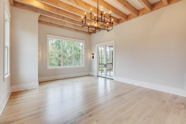 spare room featuring beam ceiling, french doors, light wood-type flooring, and baseboards