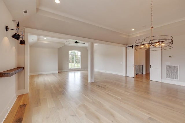 interior space featuring visible vents, light wood-style flooring, a barn door, baseboards, and ceiling fan