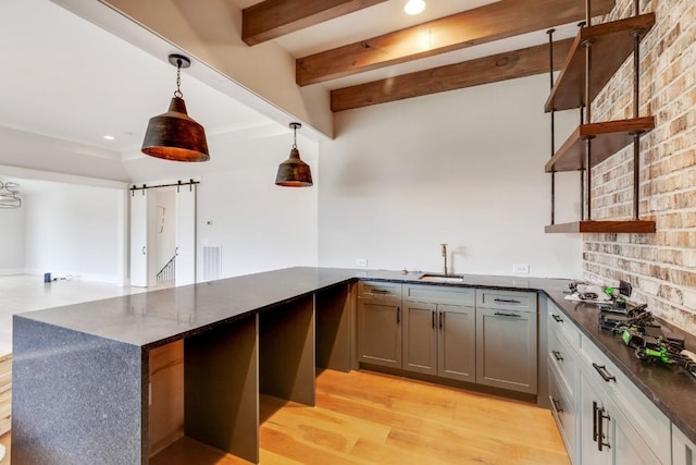 kitchen featuring visible vents, beamed ceiling, open shelves, a sink, and a barn door