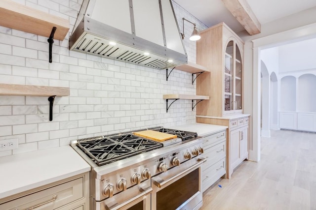 kitchen with ventilation hood, open shelves, range with two ovens, beamed ceiling, and tasteful backsplash