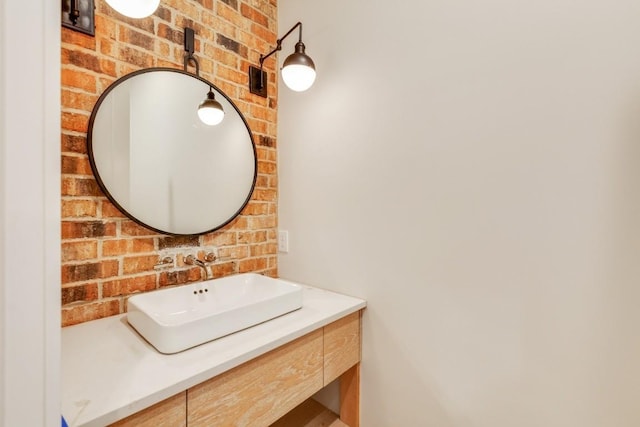 bathroom featuring brick wall and vanity