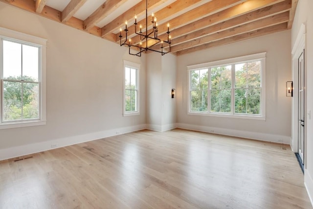 unfurnished room with a wealth of natural light, beam ceiling, and wood finished floors