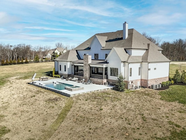 rear view of property featuring a yard, a shingled roof, central AC unit, a chimney, and a patio area