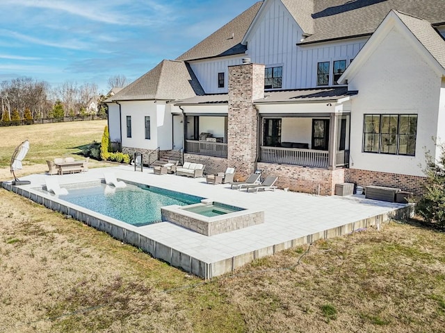 rear view of house with a patio, fence, roof with shingles, an in ground hot tub, and board and batten siding