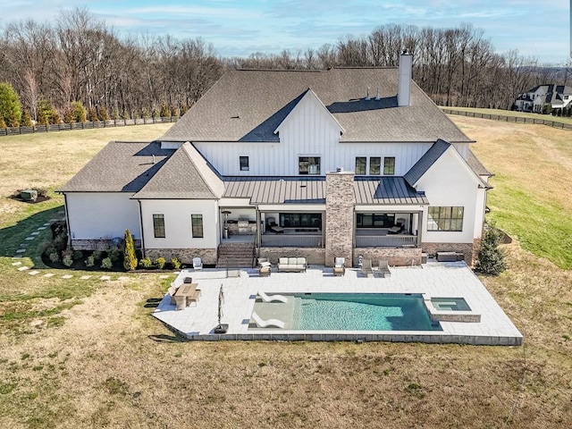 rear view of property with a standing seam roof, a patio area, a yard, and roof with shingles