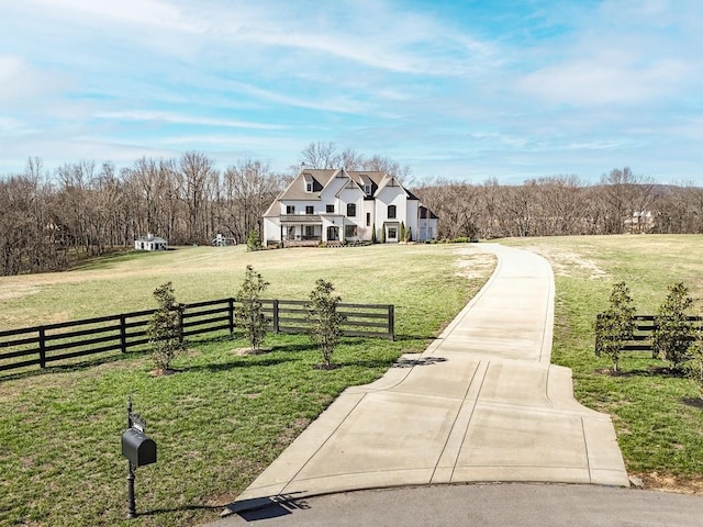 view of home's community with a fenced front yard, a rural view, and a lawn