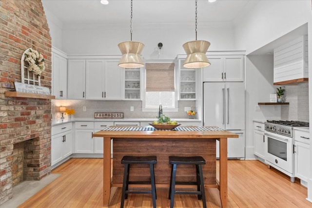 kitchen with premium appliances, light wood-style flooring, a kitchen breakfast bar, light countertops, and open shelves