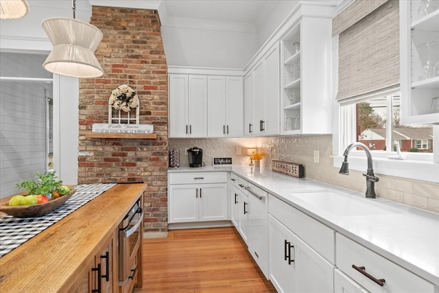 kitchen with butcher block countertops, a sink, light wood-style floors, tasteful backsplash, and crown molding