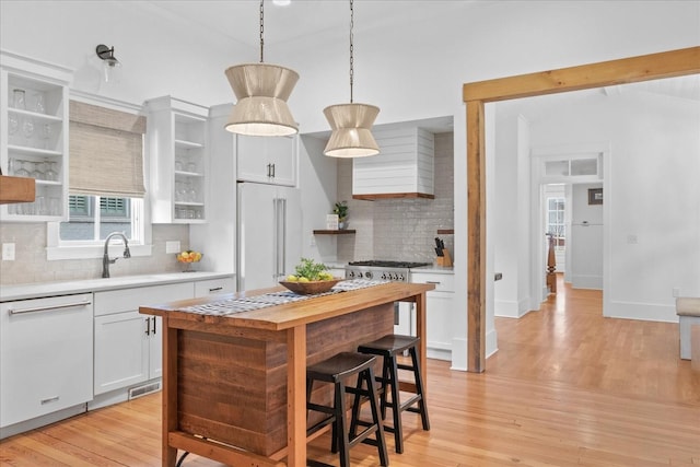 kitchen featuring built in fridge, a sink, dishwasher, open shelves, and light wood finished floors