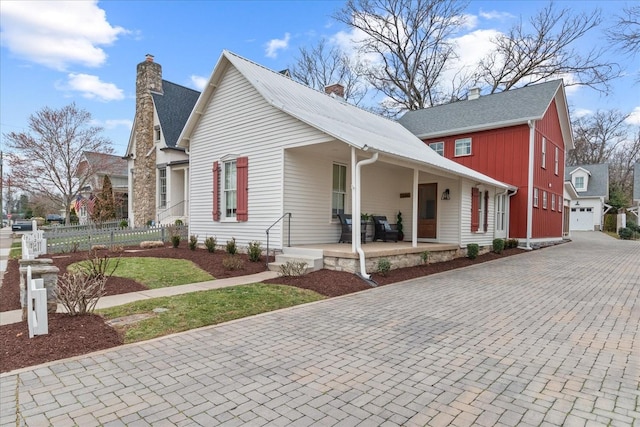 view of front of house with a chimney, fence, a porch, and decorative driveway