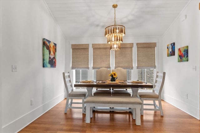 dining area featuring a chandelier, baseboards, wood finished floors, and crown molding