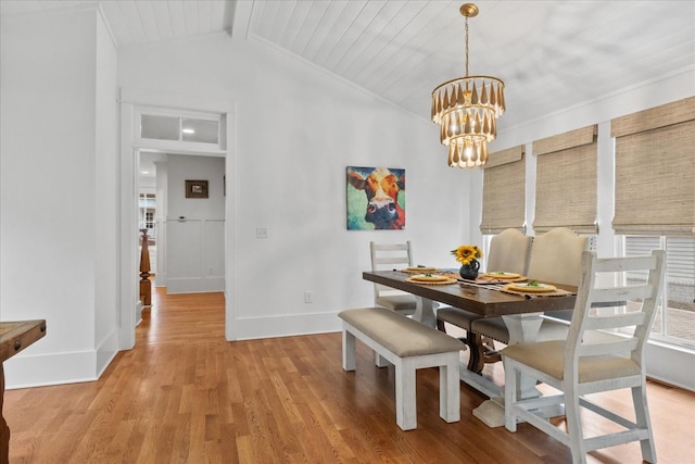 dining space featuring light wood-type flooring, a notable chandelier, lofted ceiling with beams, and baseboards