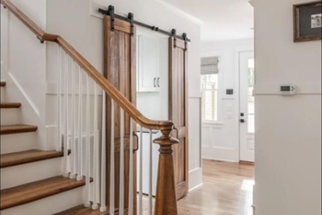 staircase featuring a barn door and wood finished floors