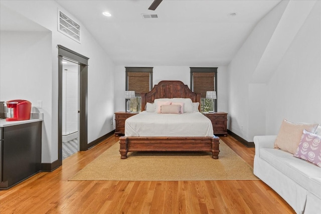 bedroom featuring a ceiling fan, light wood-style flooring, visible vents, and baseboards