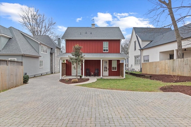 rear view of house with fence, decorative driveway, a yard, a porch, and board and batten siding