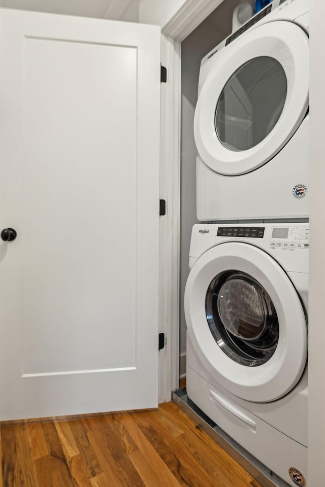 laundry area featuring laundry area, stacked washing maching and dryer, and wood finished floors