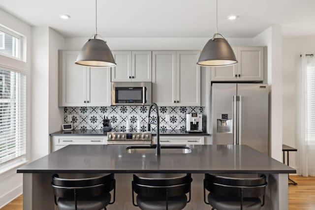 kitchen featuring appliances with stainless steel finishes, backsplash, dark countertops, and a sink