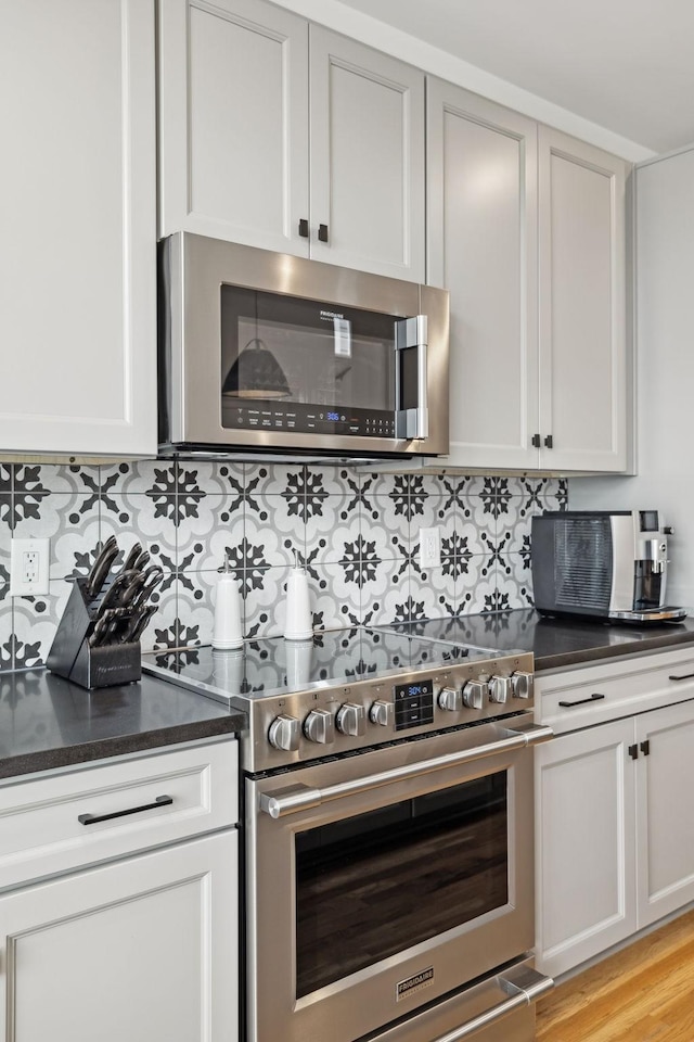 kitchen featuring light wood finished floors, stainless steel appliances, and tasteful backsplash