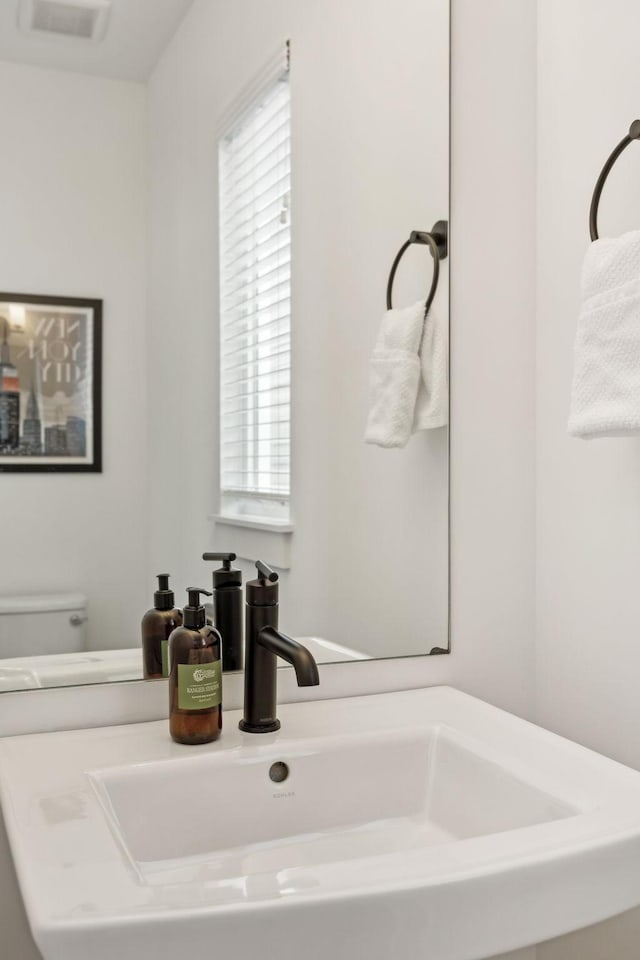 half bathroom featuring visible vents, a sink, and toilet