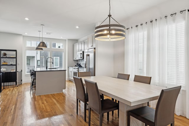 dining room with light wood-type flooring, baseboards, a chandelier, and recessed lighting