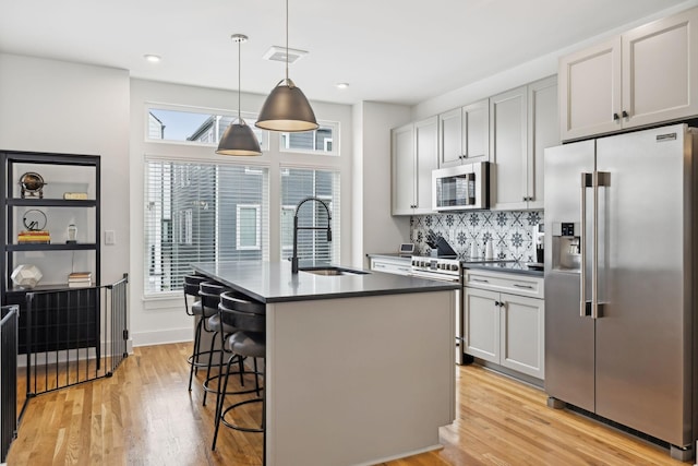 kitchen with light wood finished floors, visible vents, dark countertops, stainless steel appliances, and a sink