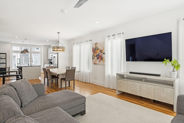 living room with light wood-type flooring, baseboards, and recessed lighting