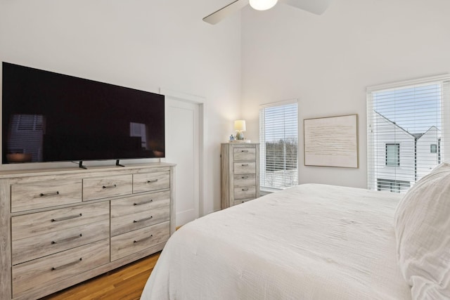 bedroom featuring ceiling fan, a towering ceiling, and wood finished floors