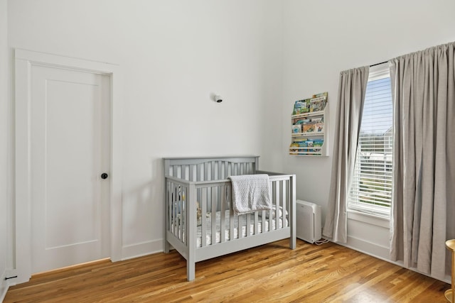 bedroom featuring a crib, baseboards, and wood finished floors