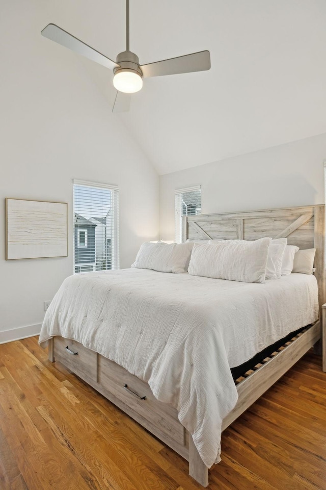 bedroom with multiple windows, vaulted ceiling, and wood finished floors