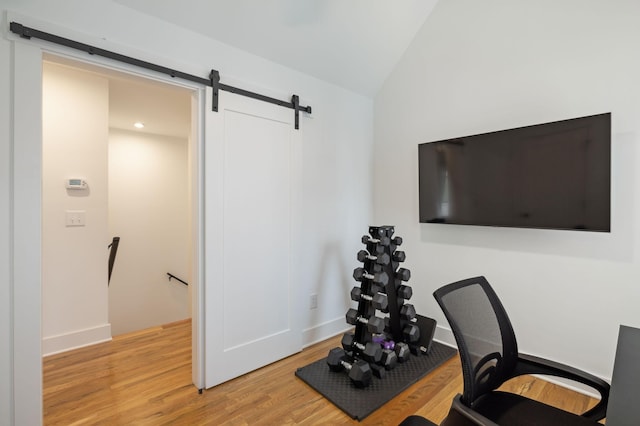 home office featuring lofted ceiling, a barn door, and light wood-style flooring