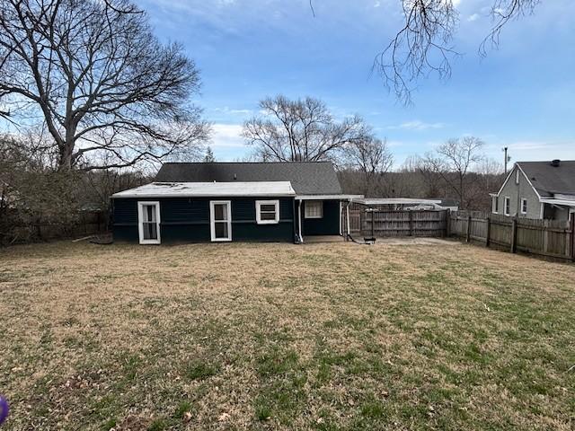 rear view of property with a yard and a fenced backyard