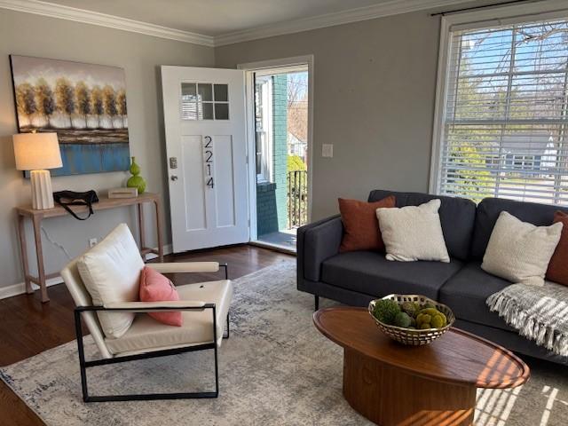 living room featuring crown molding, baseboards, and wood finished floors