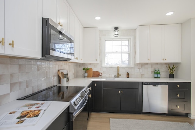 kitchen with stainless steel appliances, light countertops, light wood-type flooring, and white cabinets